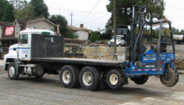 A picture of a flatbed with a loader on piggy back.